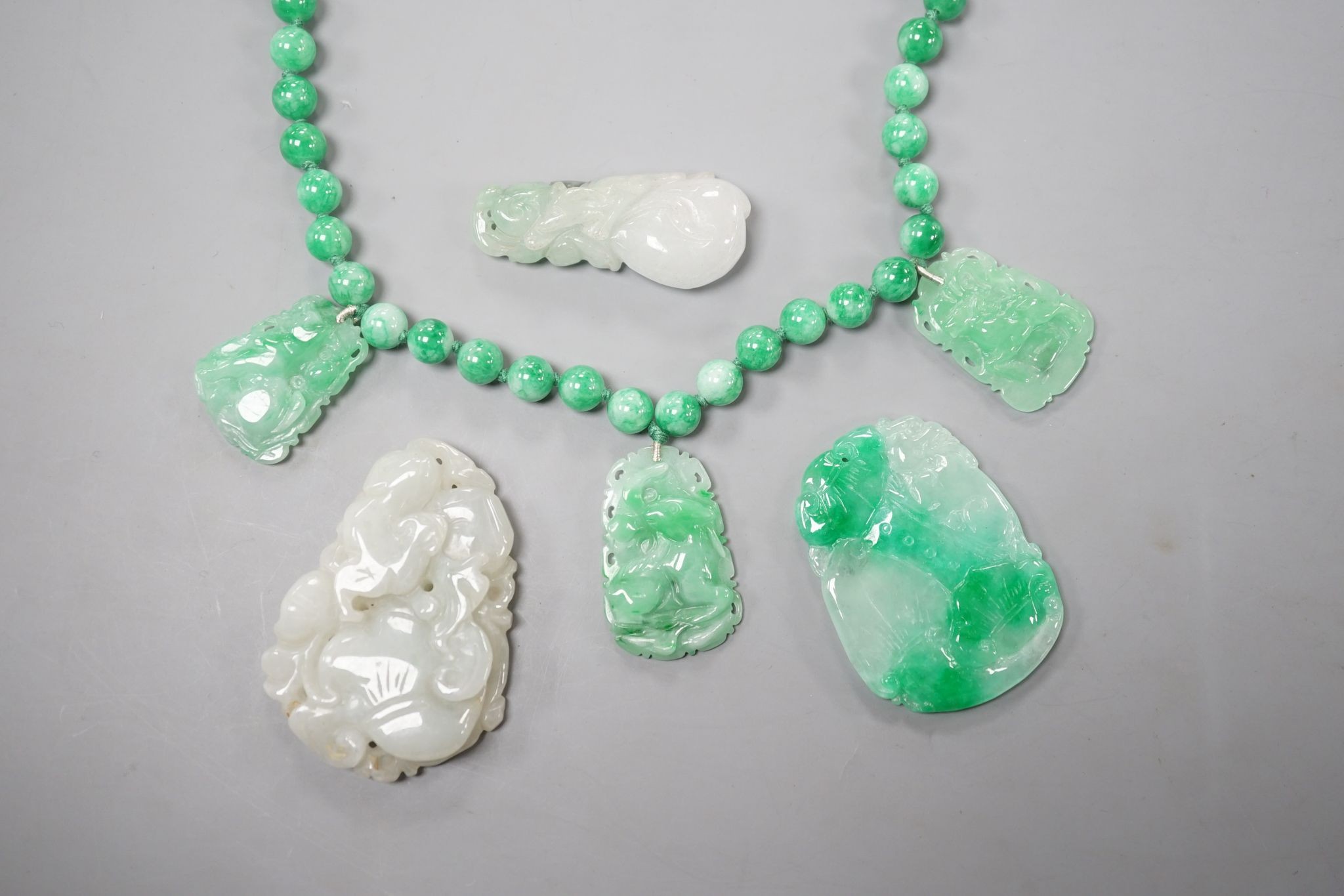 A jade bead necklace hung with three jade carvings, 49cm and three other jade carvings.